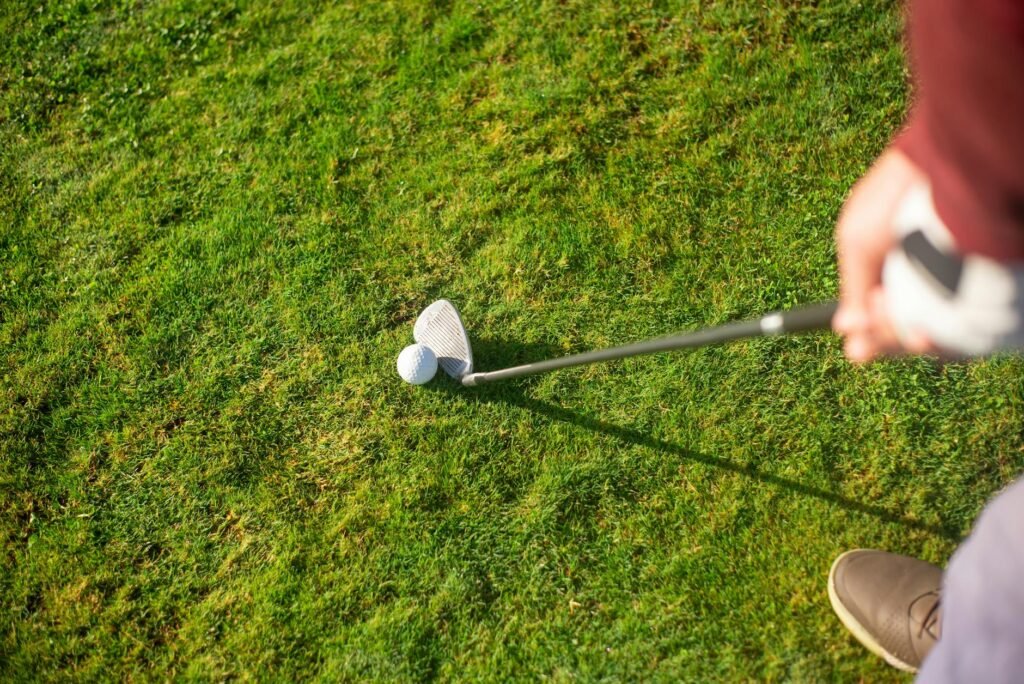 Close-up view of a golfer ready to swing with a club on a lush green grass field.